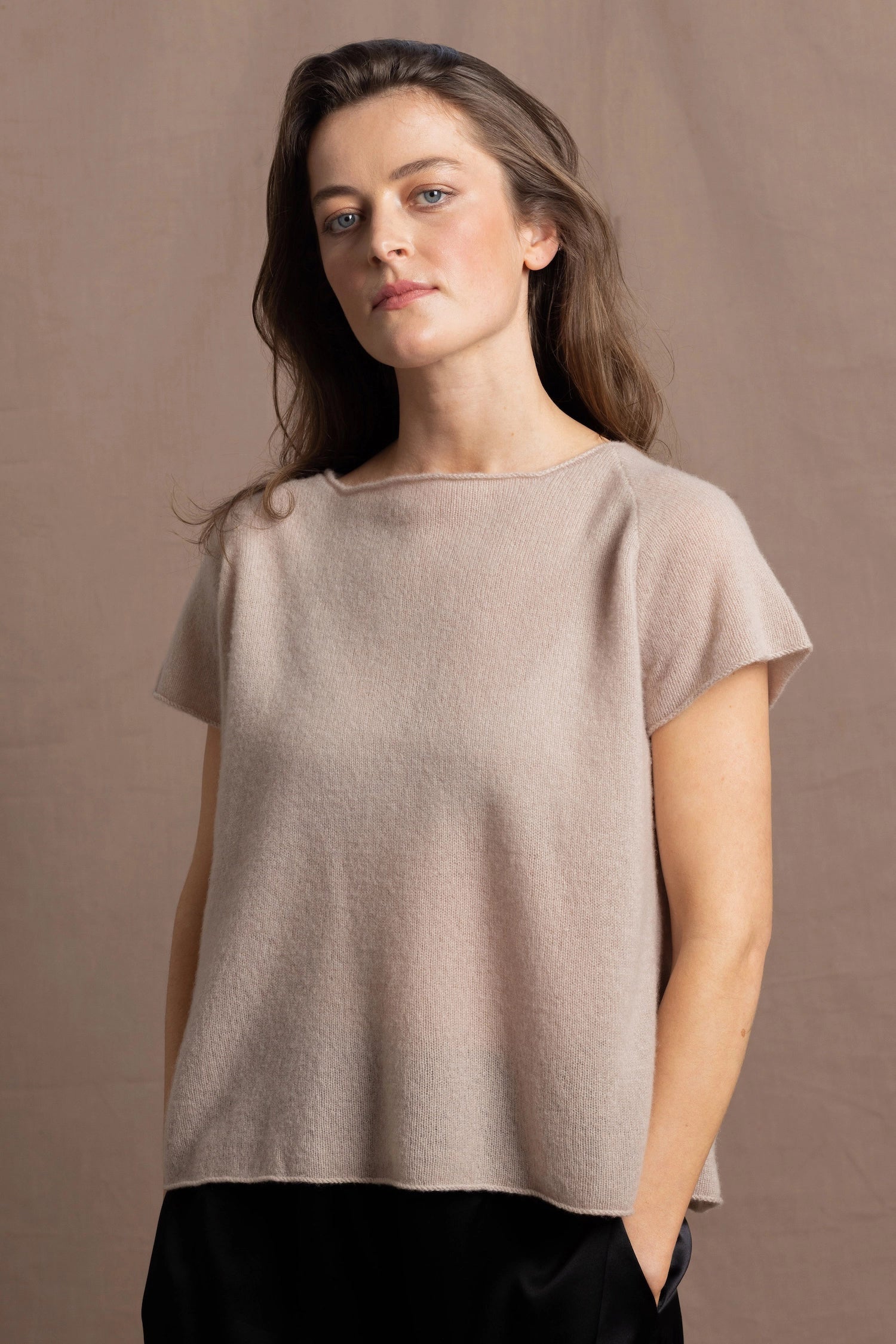 A woman wears a 100% cashmere tshirt in beige with pure silk shorts in black
