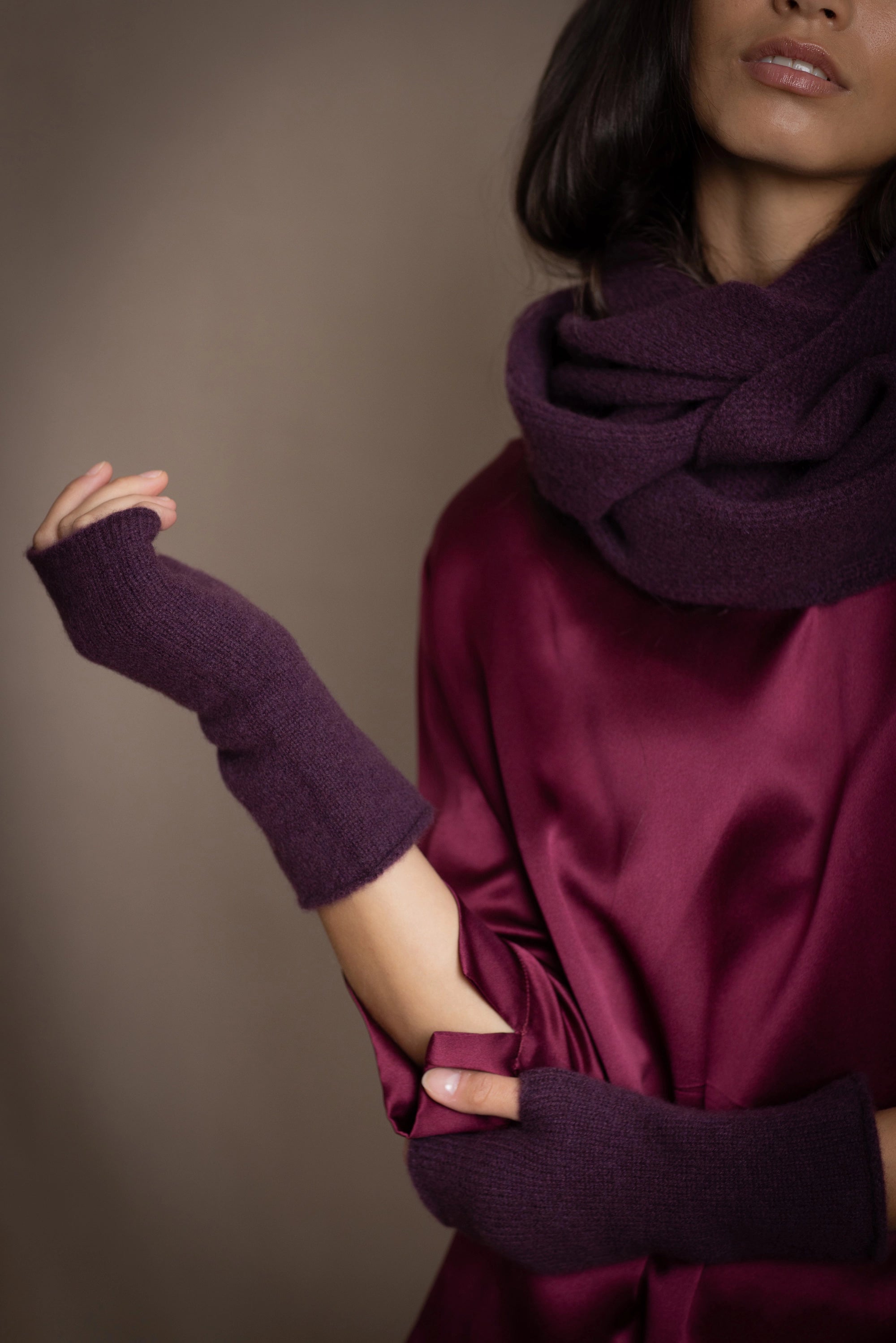 a woman wearing cashmere fingerless gloves in dark purple with burgundy silk top and matching cashmere snood in dark purple