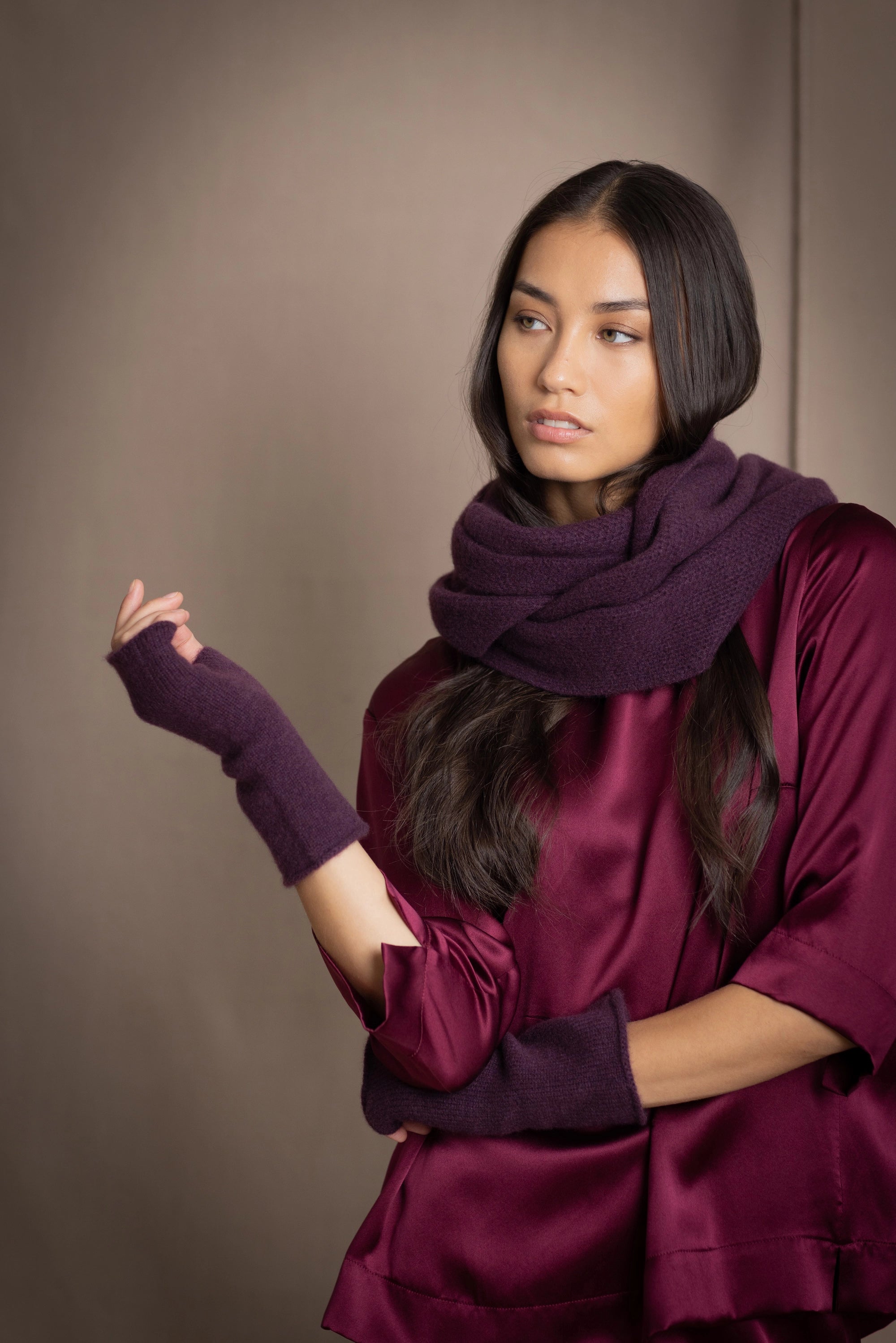 a woman wearing cashmere fingerless gloves in dark purple with burgundy silk top and matching cashmere snood in dark purple