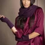 a woman wearing cashmere fingerless gloves in dark purple with burgundy silk top and matching cashmere snood in dark purple