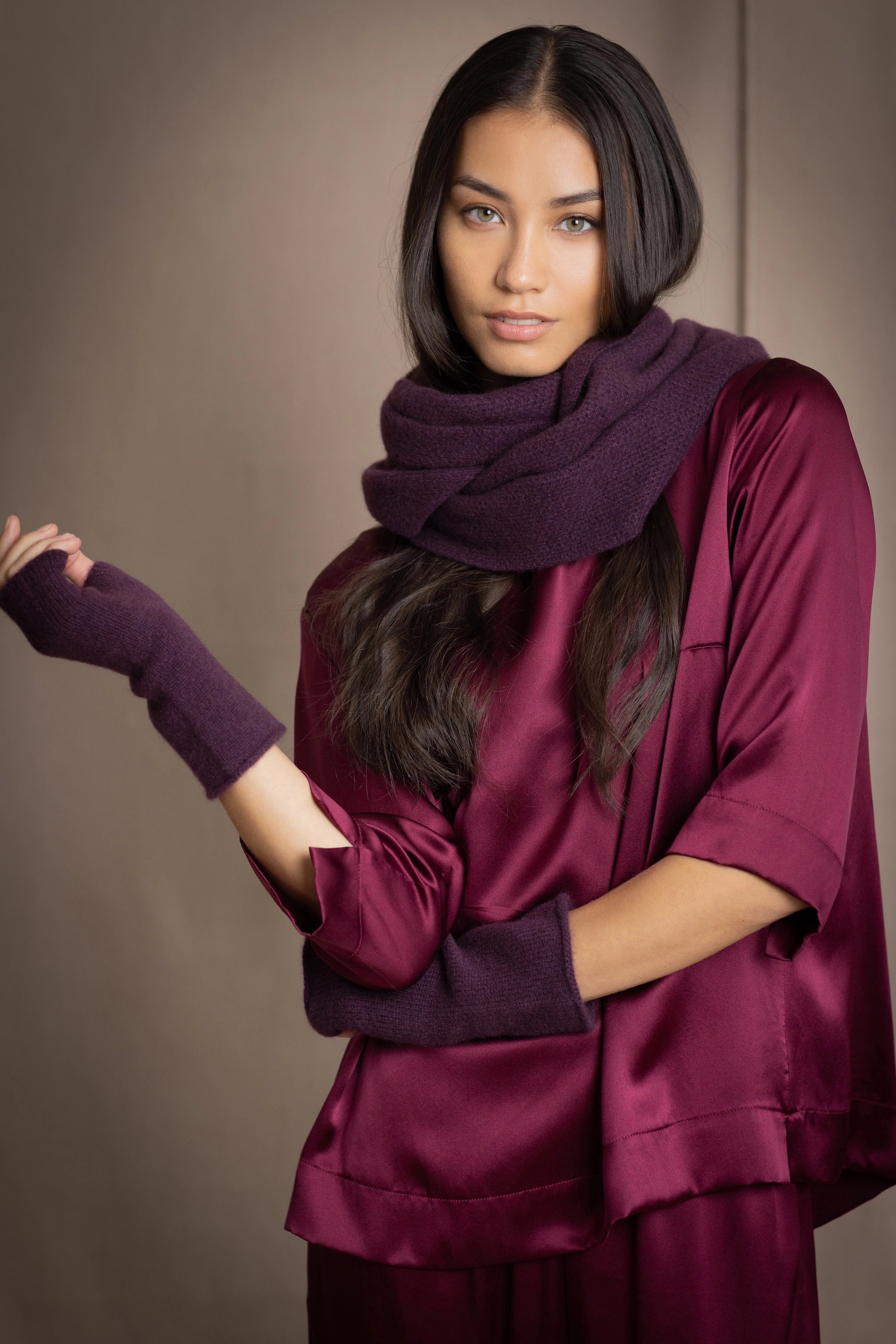 a woman wearing cashmere fingerless gloves in dark purple with burgundy silk top and matching cashmere snood in dark purple