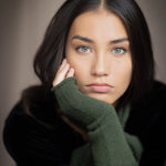 a woman wearing cashmere fingerless gloves in green and small cashmere scarf in green over silk velvet top in black