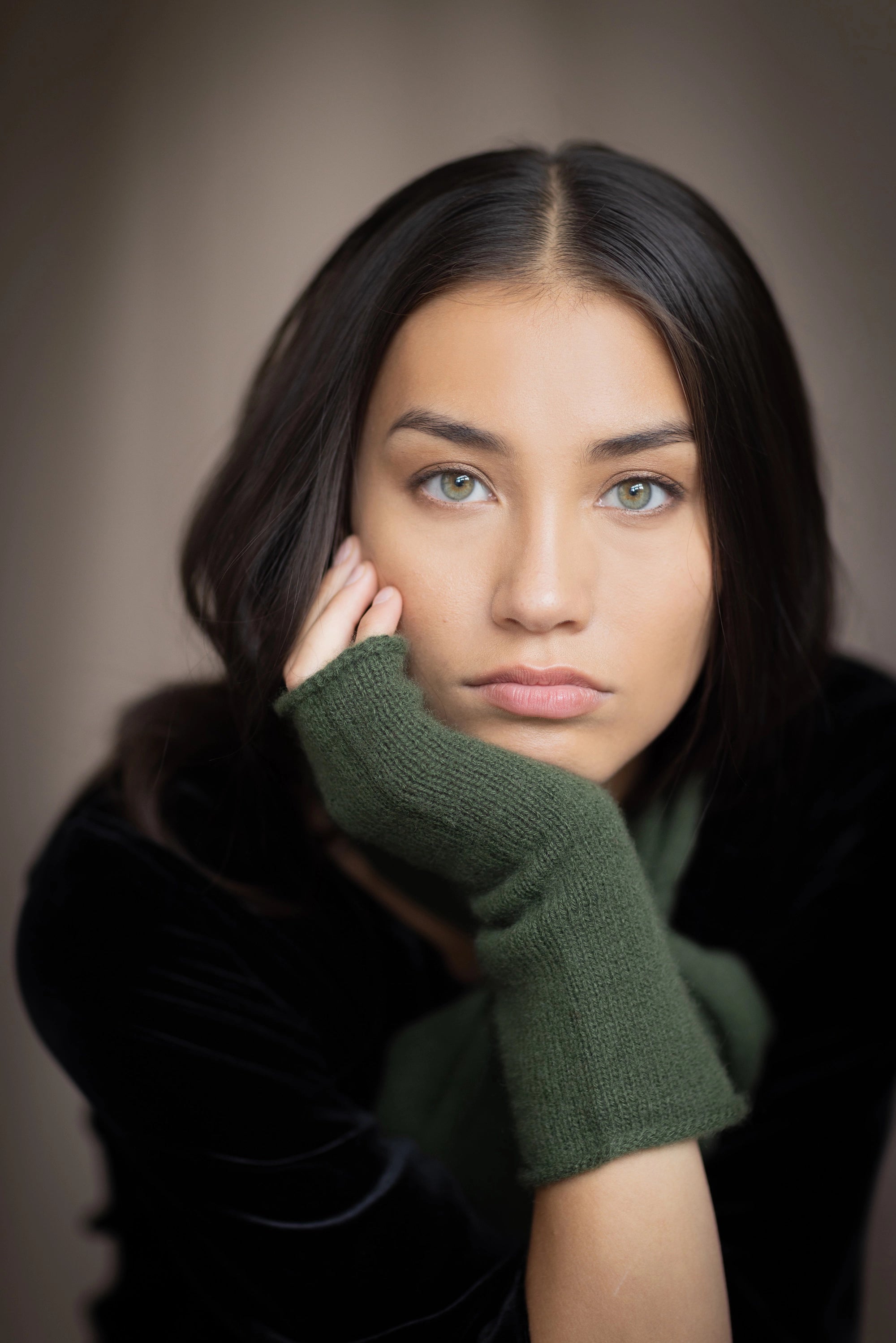 a woman wearing cashmere fingerless gloves in green and small cashmere scarf in green over silk velvet top in black