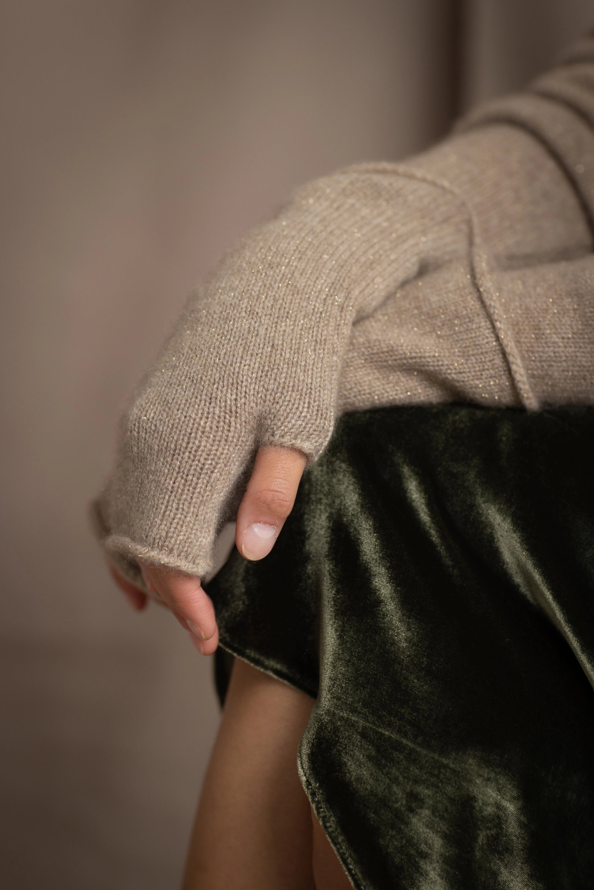 close up of cashmere fingerless gloves in beige with a metallic gold lurex thread through them