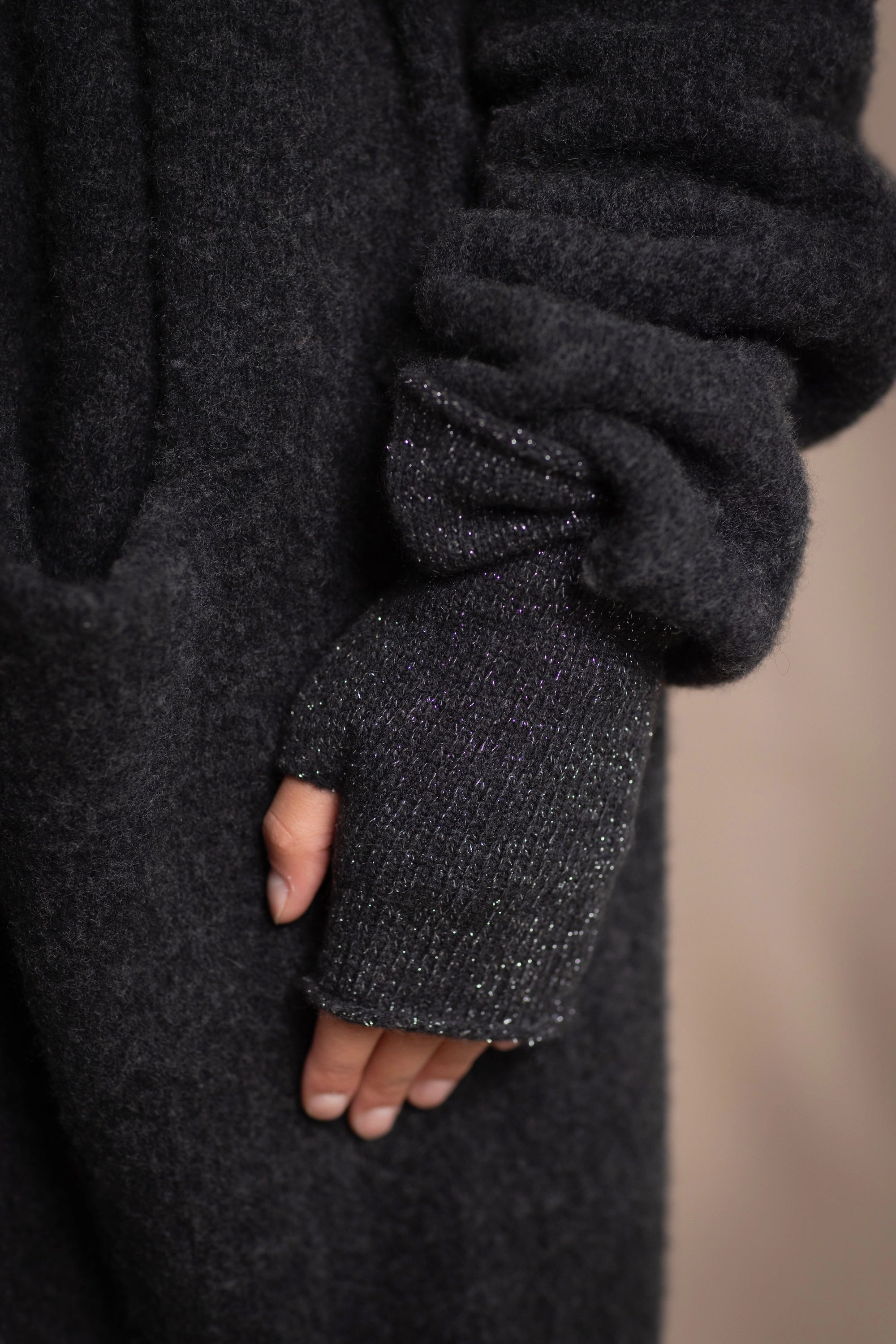 a close up of cashmere fingerless gloves in black with a metallic silver lurex thread through them