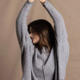 A woman wears a pure cashmere sweater that is oversized in grey