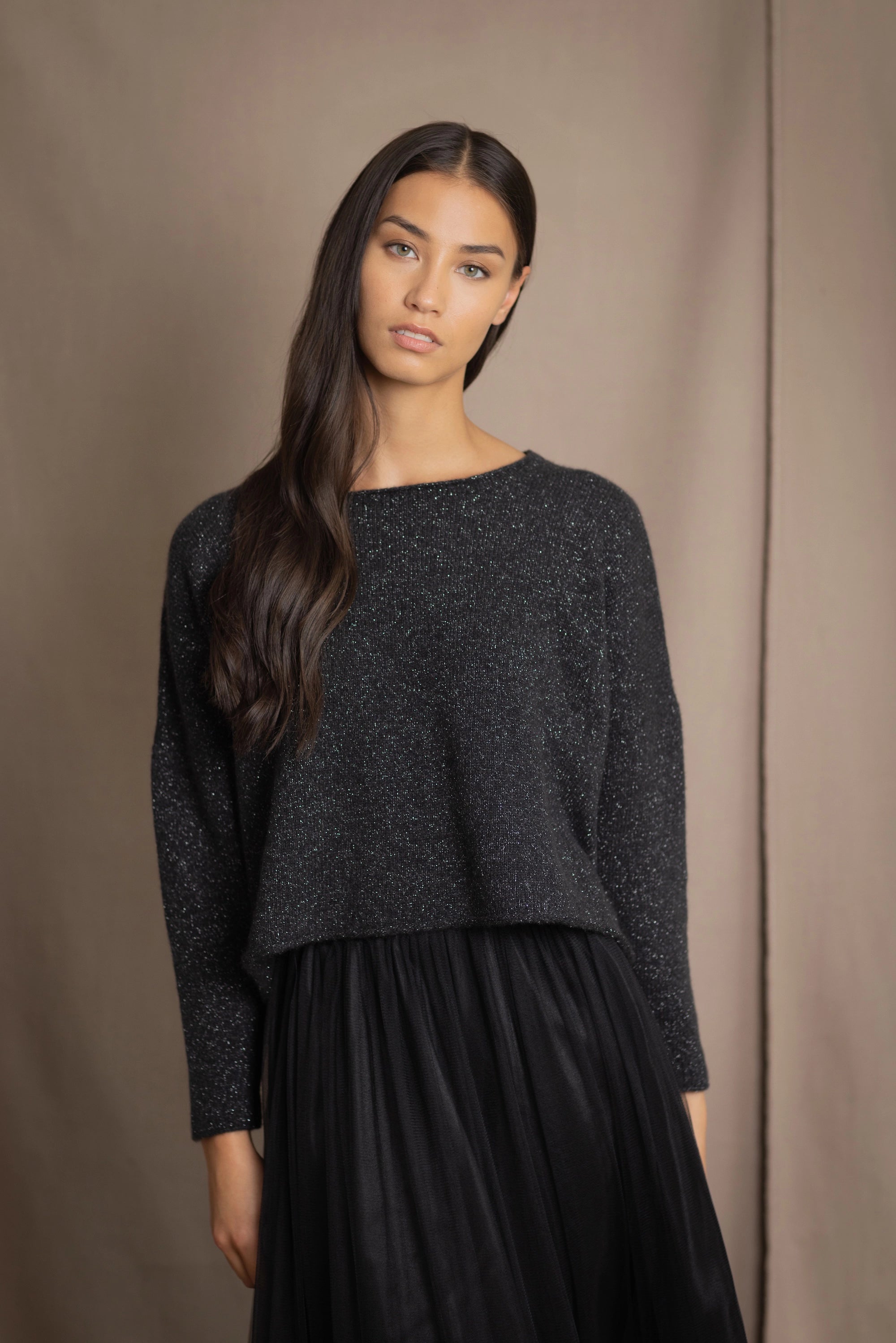 a woman wearing a cropped cashmere oversized cashmere sweater in black with metallic silver lurex thread and tulle skirt in black