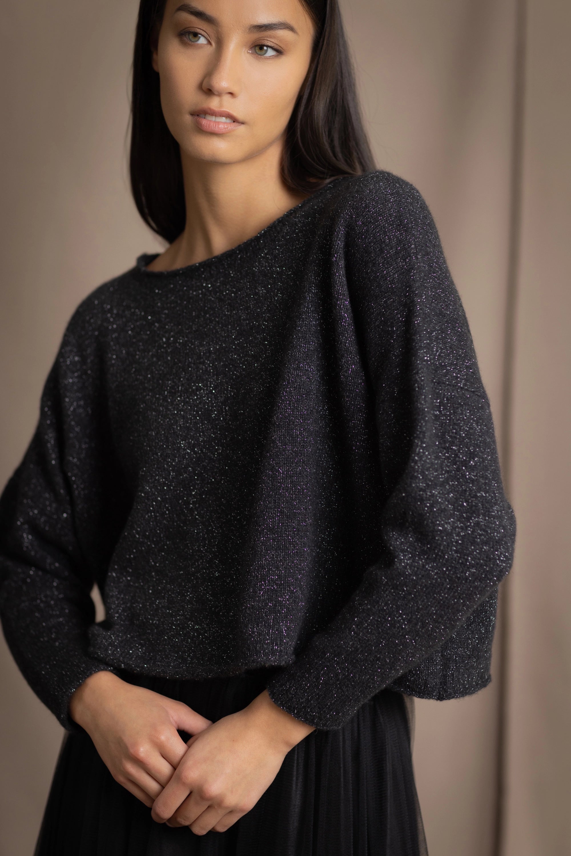 a woman wearing a cropped cashmere oversized cashmere sweater in black with metallic silver lurex thread and tulle skirt in black