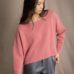 a woman wearing a cropped cashmere oversized cashmere sweater in dusty rose pink over silk trousers in pewter grey