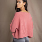 a woman wearing a cropped cashmere oversized cashmere sweater in dusty rose pink over silk trousers in pewter grey