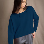 Woman wearing a blue teal cashmere sweater and gray silk pants