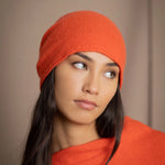 a woman wears a cashmere beanie hat in orange
