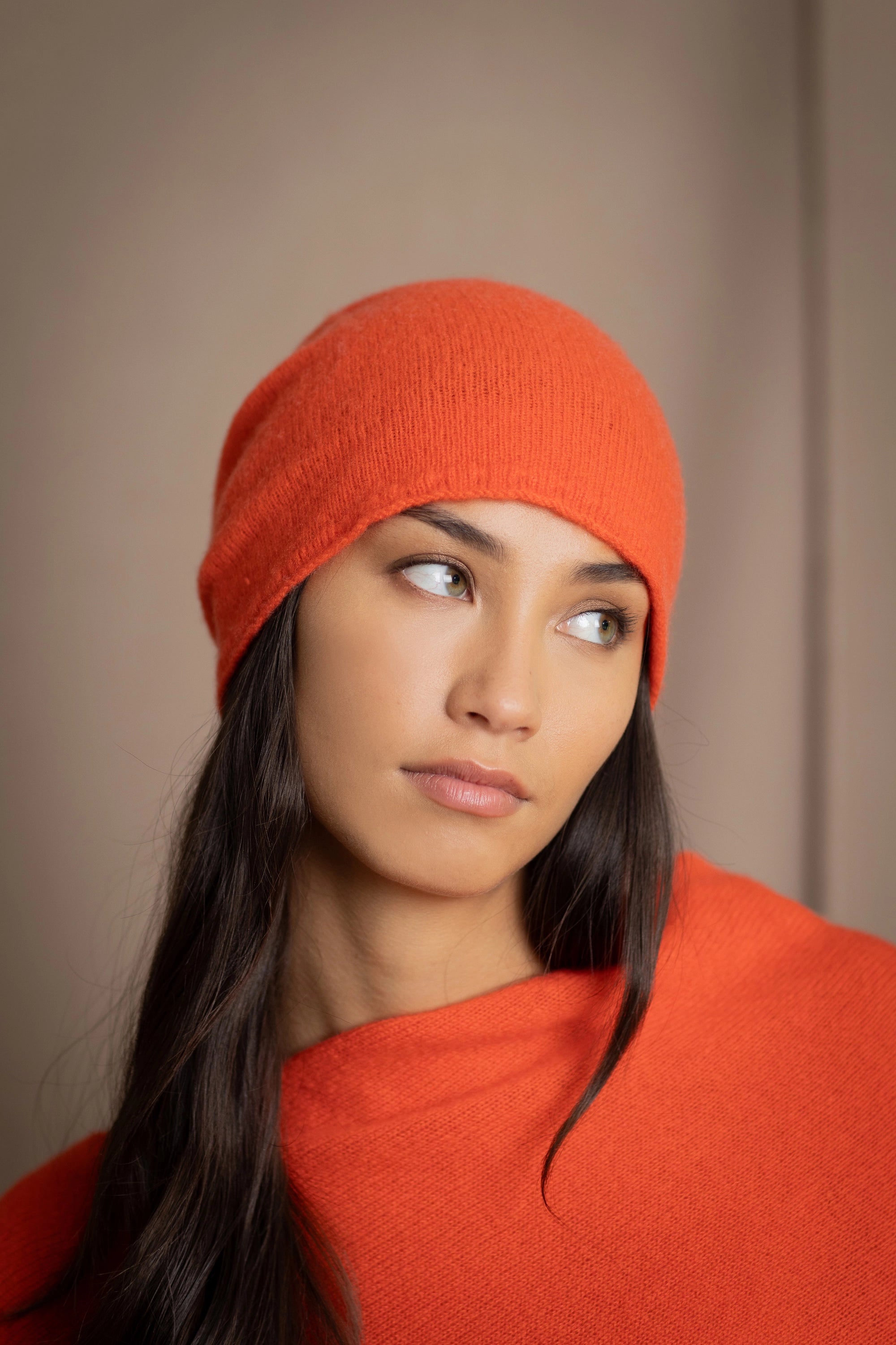 a woman wears a cashmere beanie hat in orange