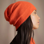 a woman wears a cashmere beanie hat in orange