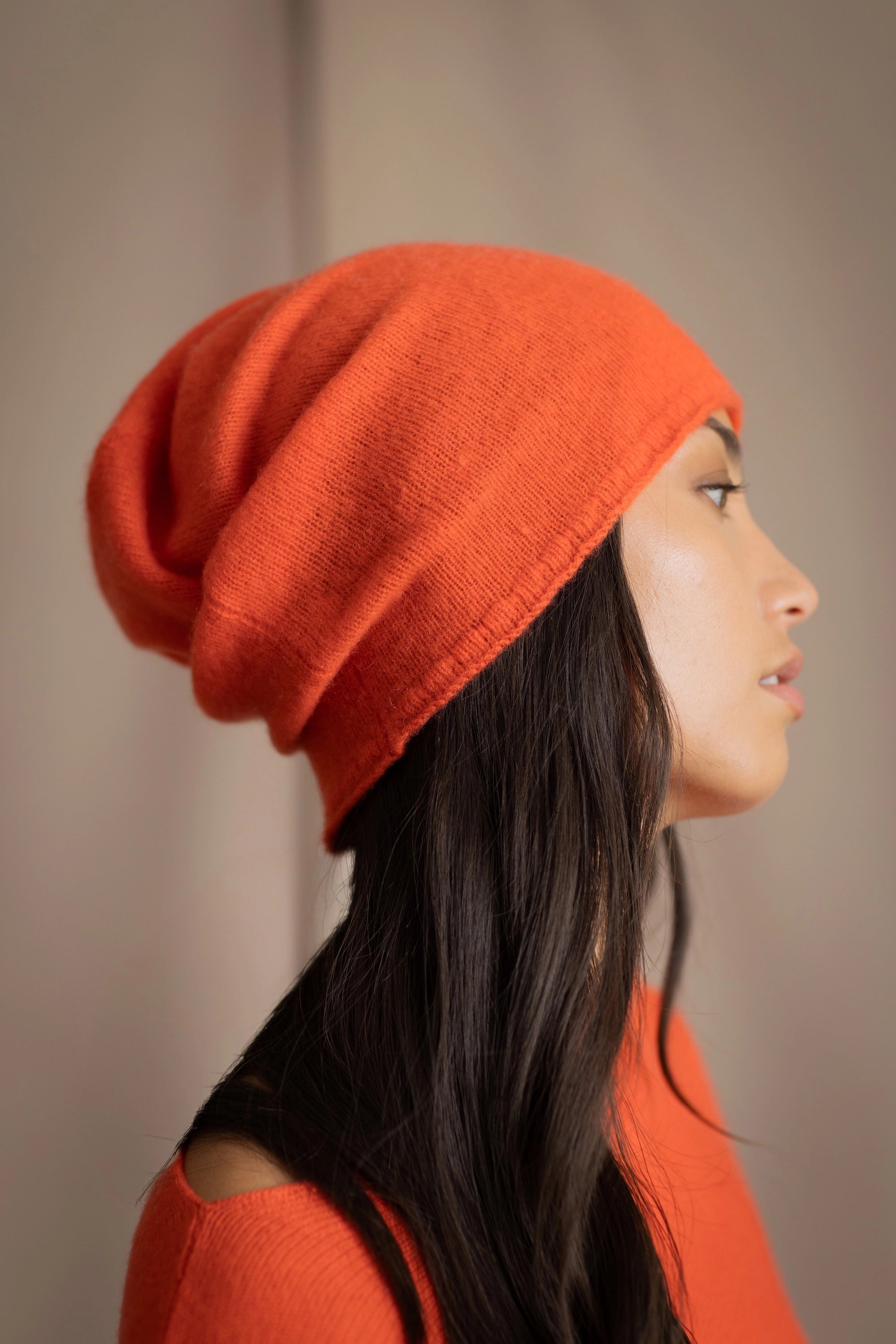 a woman wears a cashmere beanie hat in orange