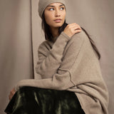 woman wears a cashmere beanie hat in beige with metallic gold lurex thread