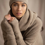a woman wearing a cashmere snood in beige with metallic gold lurex thread