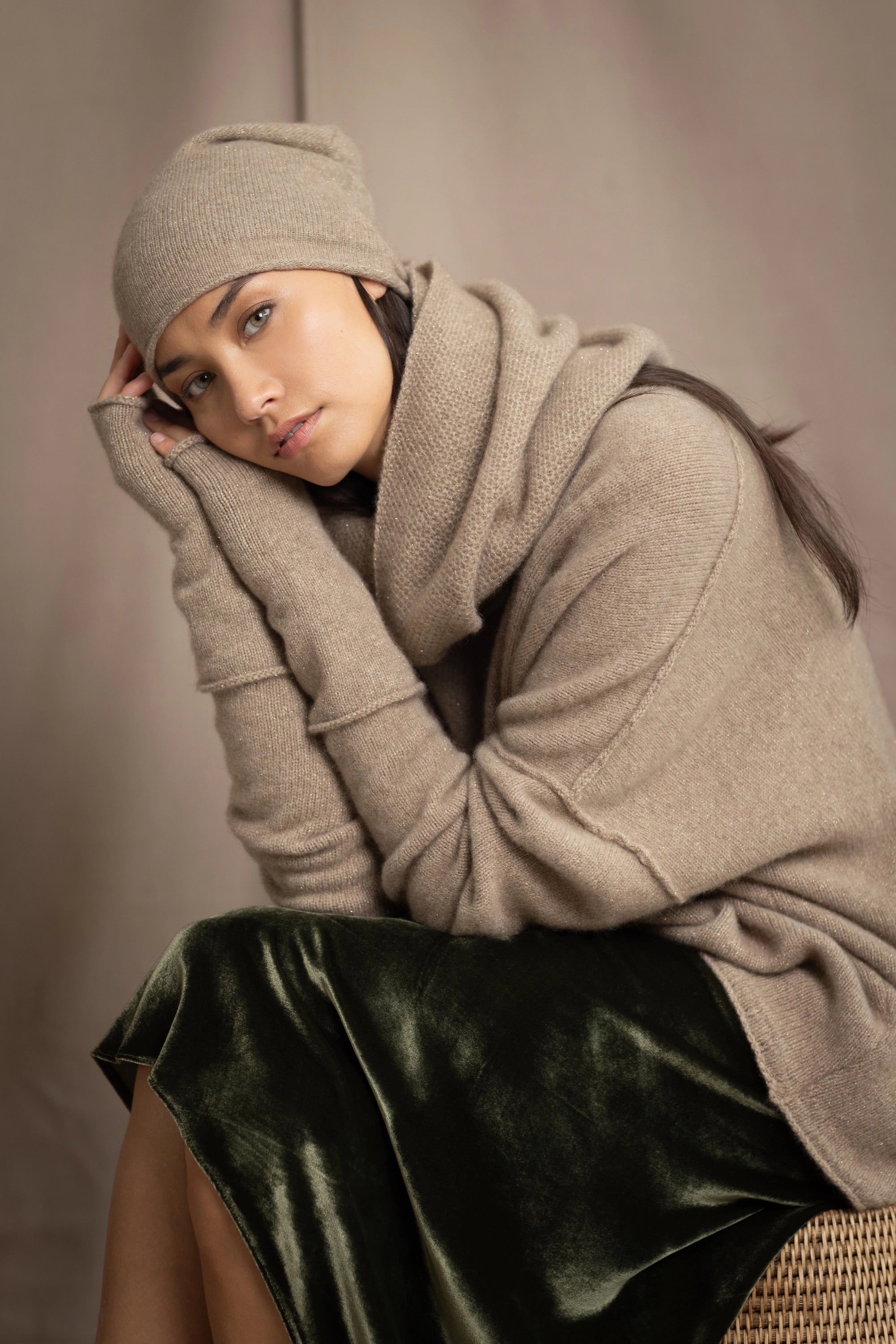 a woman wearing a cashmere snood in beige with metallic gold lurex thread