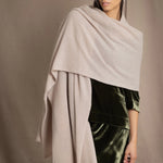 a woman wears a cashmere wrap shawl in beige with matching beanie hat