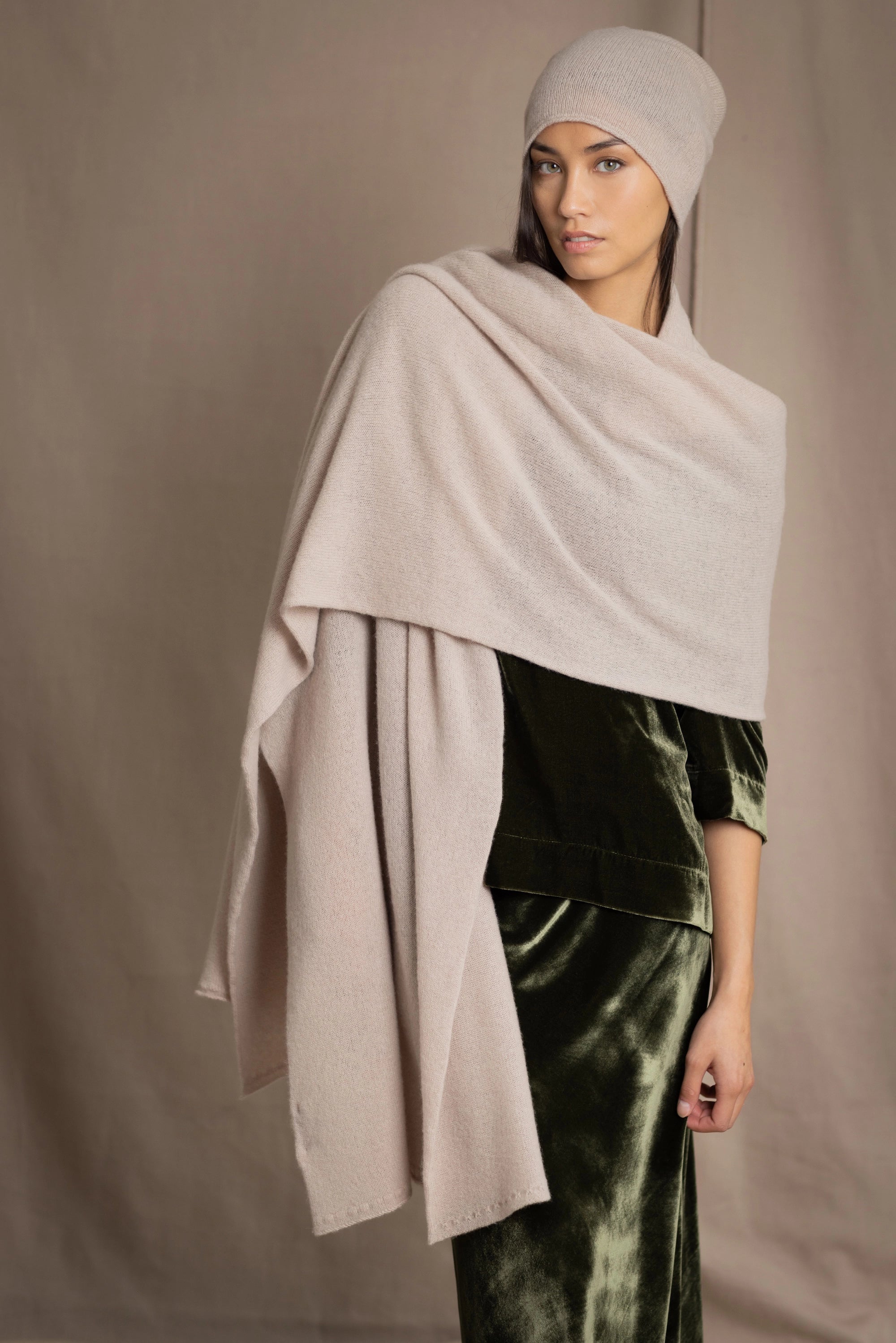 a woman wears a cashmere wrap shawl in beige with matching beanie hat