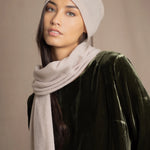 a woman wears a cashmere beanie hat in beige with matching cashmere scarf