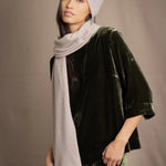 a woman wears a cashmere scarf in beige with matching cashmere beanie hat over silk velvet clothing in olive green