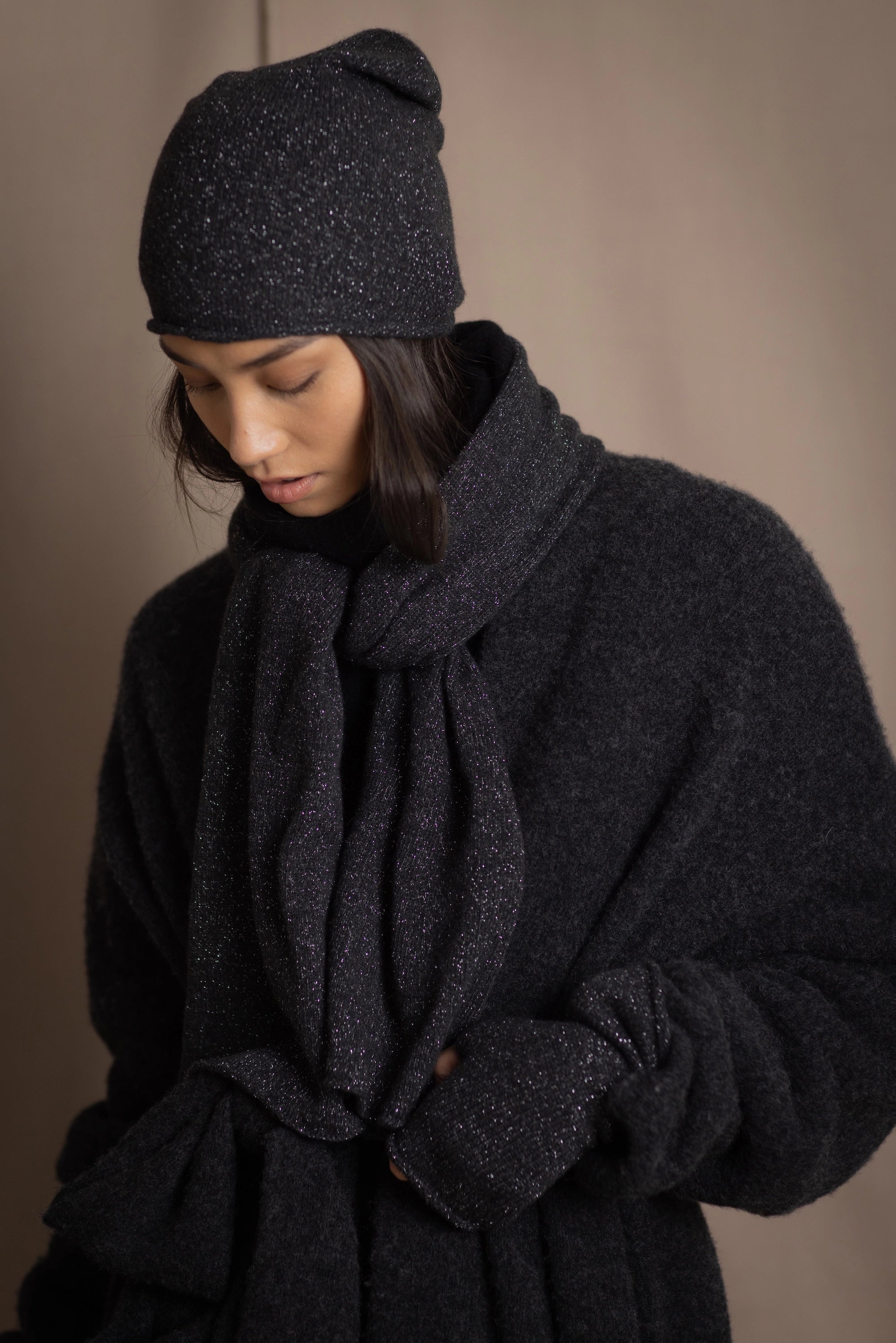 woman wears a cashmere beanie hat in black with metallic silver lurex thread