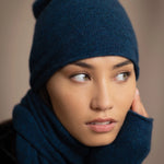 a woman wears a cashmere beanie hat in teal blue
