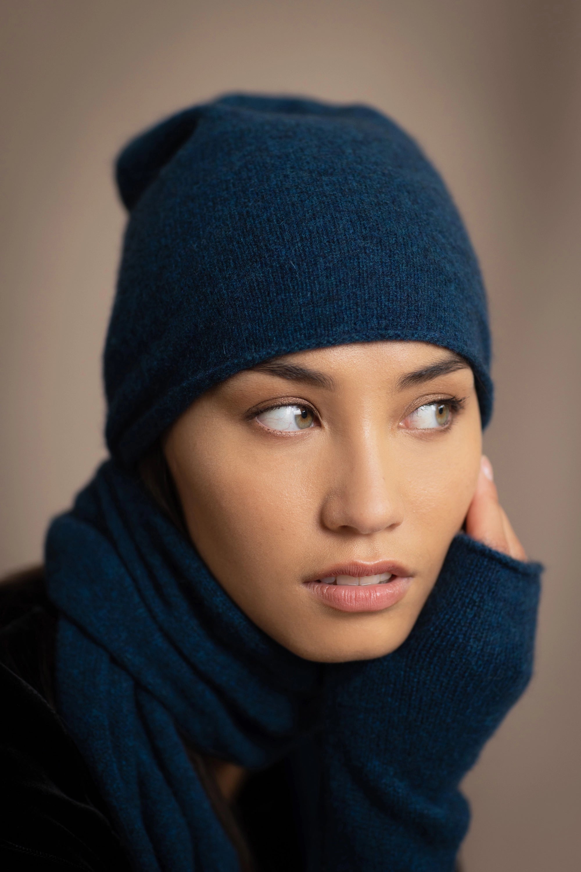 a woman wears a cashmere beanie hat in teal blue