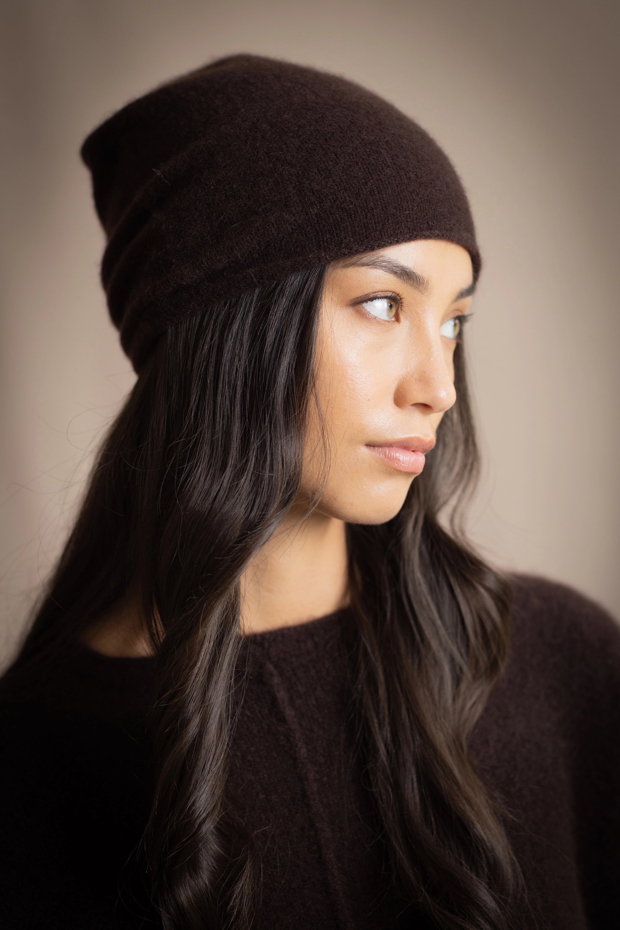 a woman wears a cashmere beanie hat in dark brown