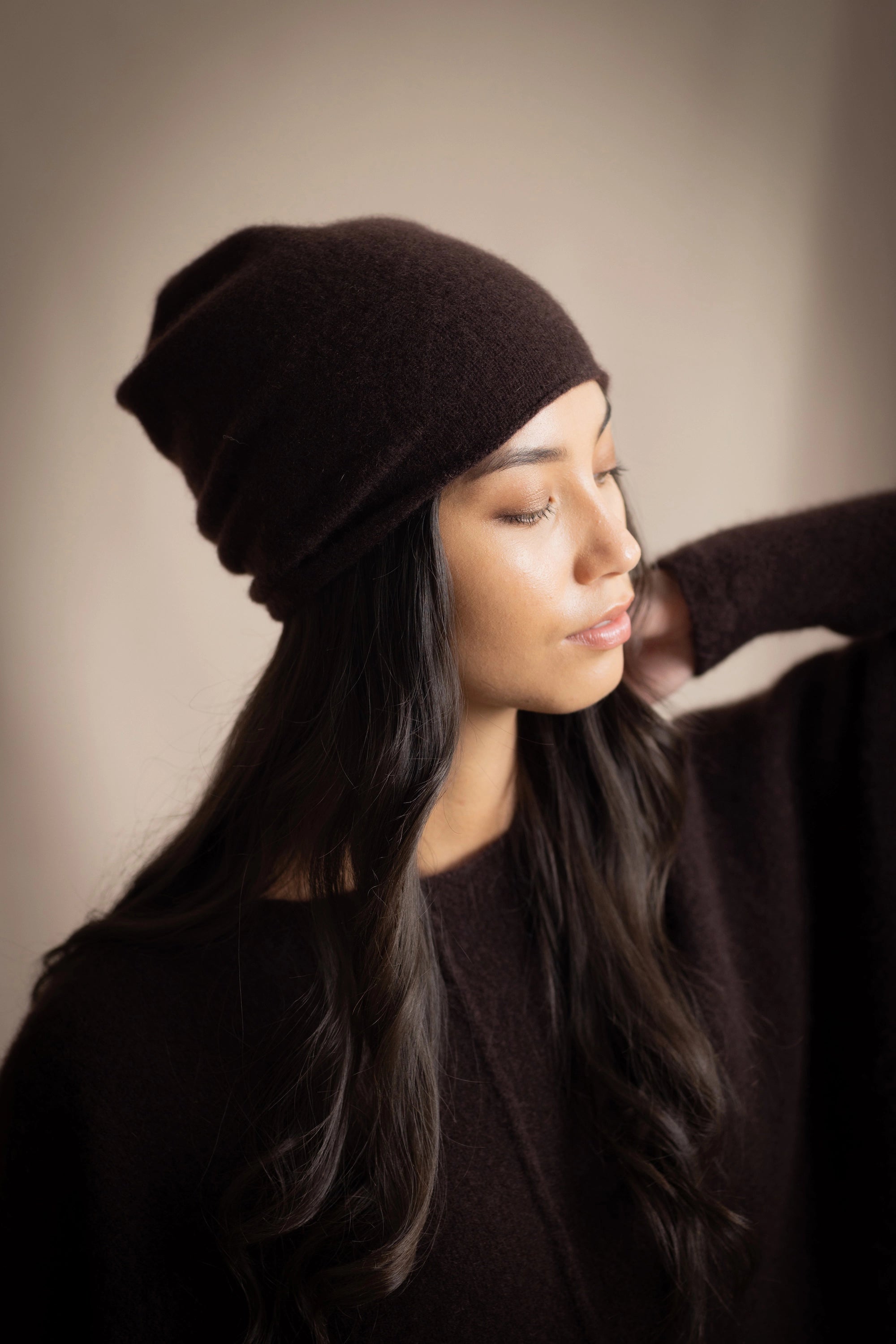 a woman wears a cashmere beanie hat in dark brown