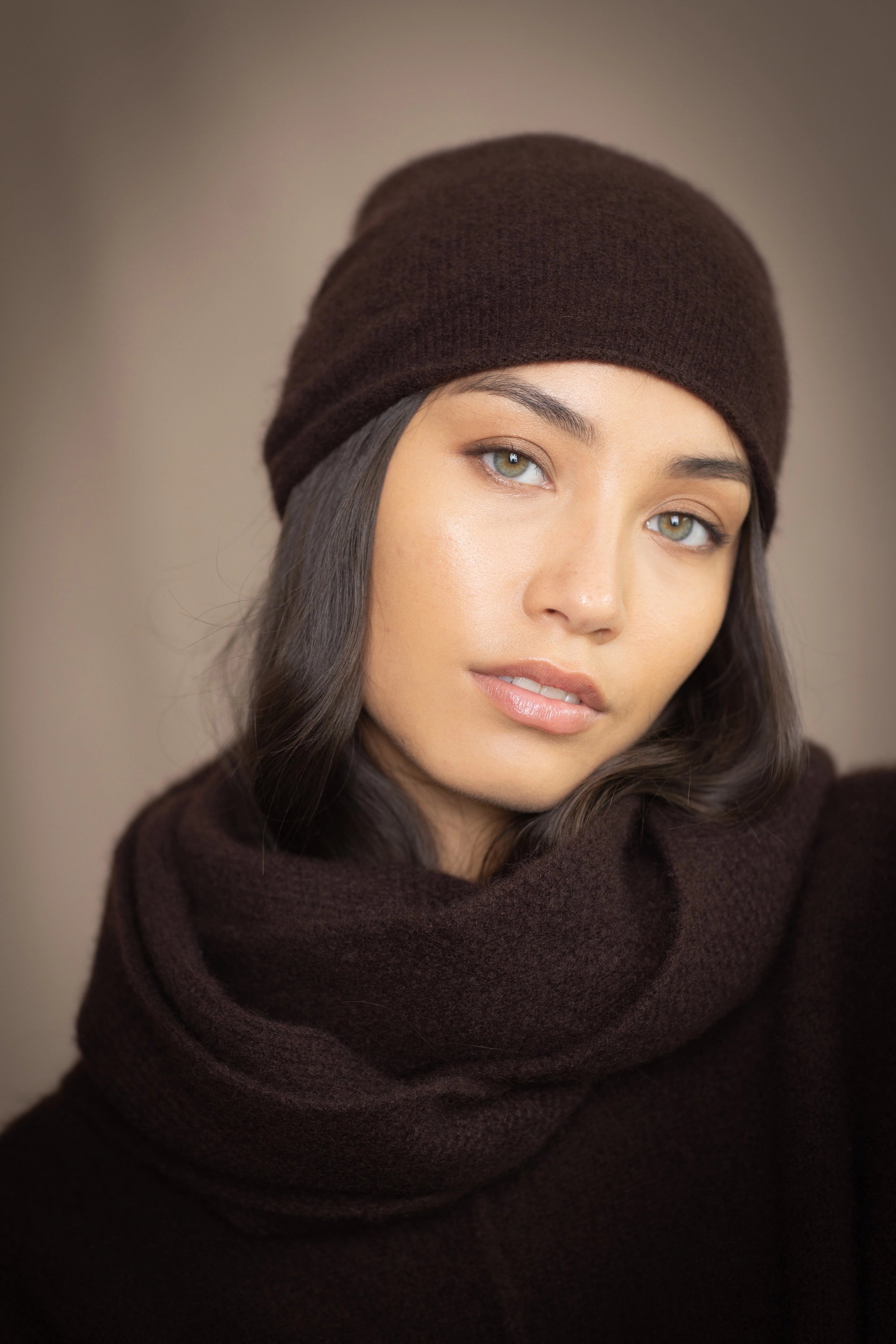 a woman wearing a cashmere snood in dark brown with matching beanie hat