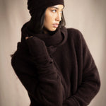a woman wearing cashmere fingerless gloves in dark brown with matching cashmere beanie hat and cashmere snood and cashmere sweater