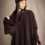 a woman wearing cashmere fingerless gloves in dark brown with matching cashmere beanie hat and cashmere snood and cashmere sweater with burgundy silk pants