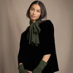 a woman wearing cashmere fingerless gloves in green and small cashmere scarf in green over silk velvet top in black
