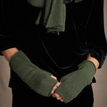a woman wearing cashmere fingerless gloves in green and small cashmere scarf in green over silk velvet top in black