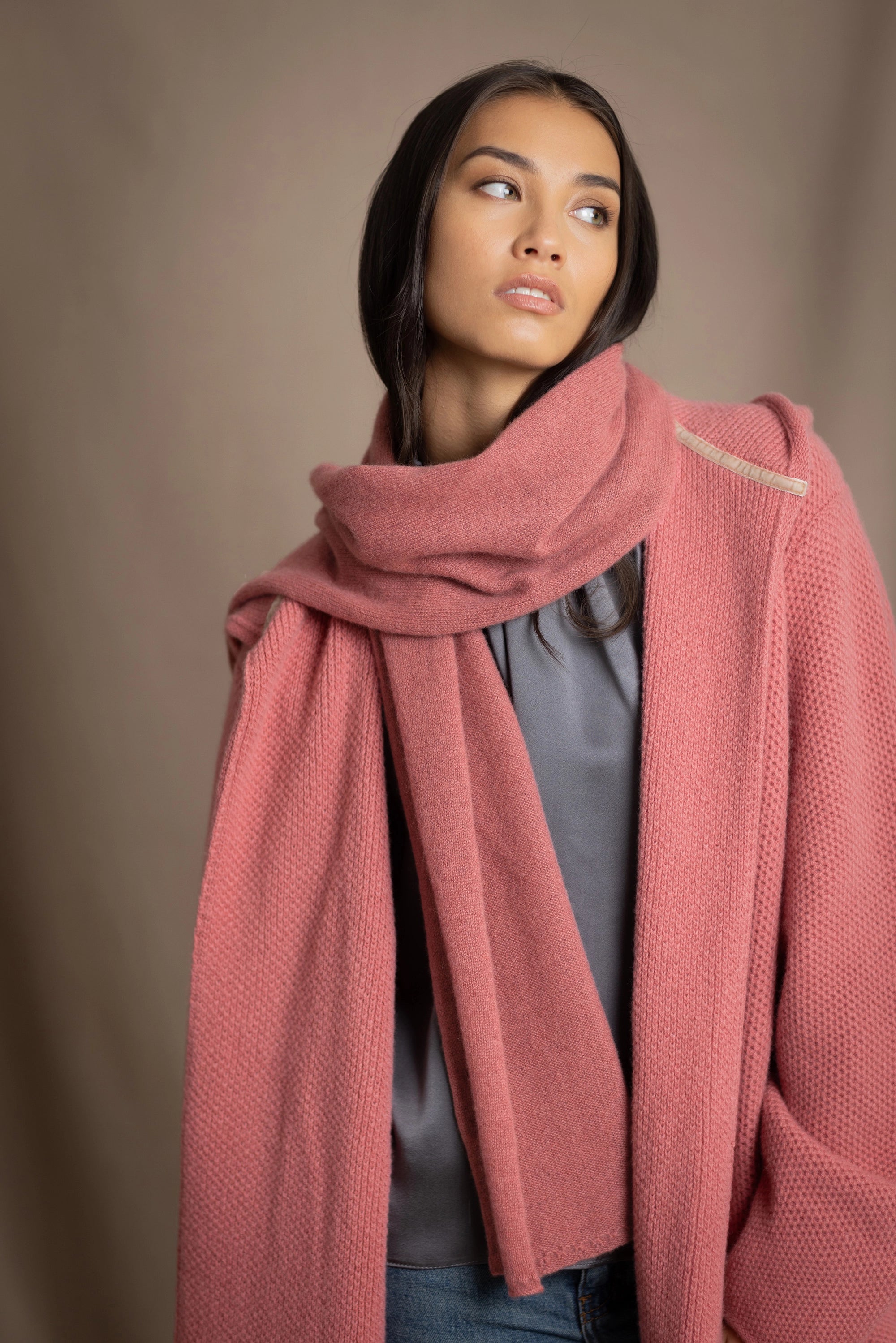 a woman wearing a cashmere scarf in dusty rose pink with matching cashmere coat cardigan