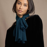 a woman wearing a cashmere scarf in teal over black silk velvet top