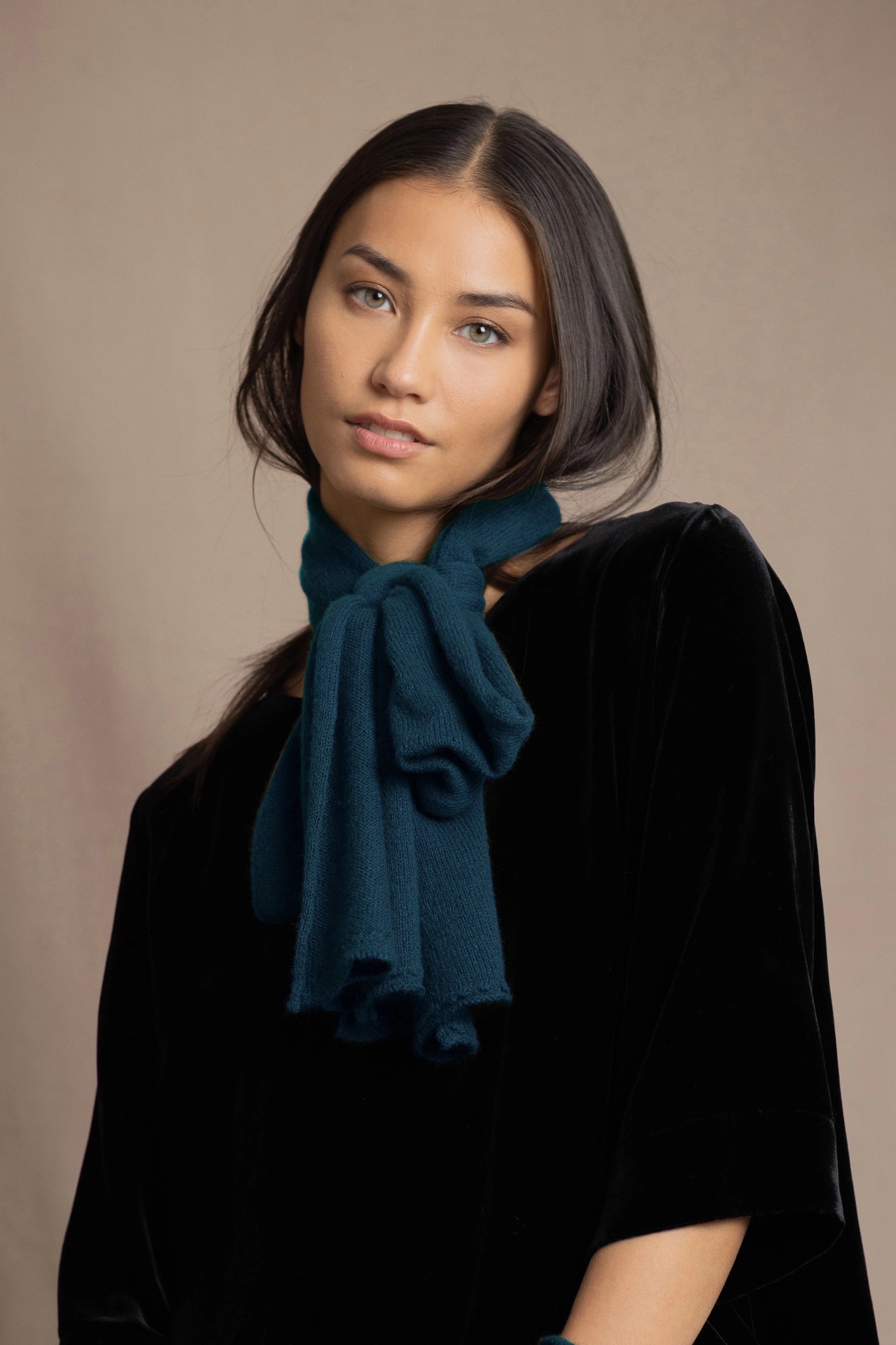 a woman wearing a cashmere scarf in teal over black silk velvet top