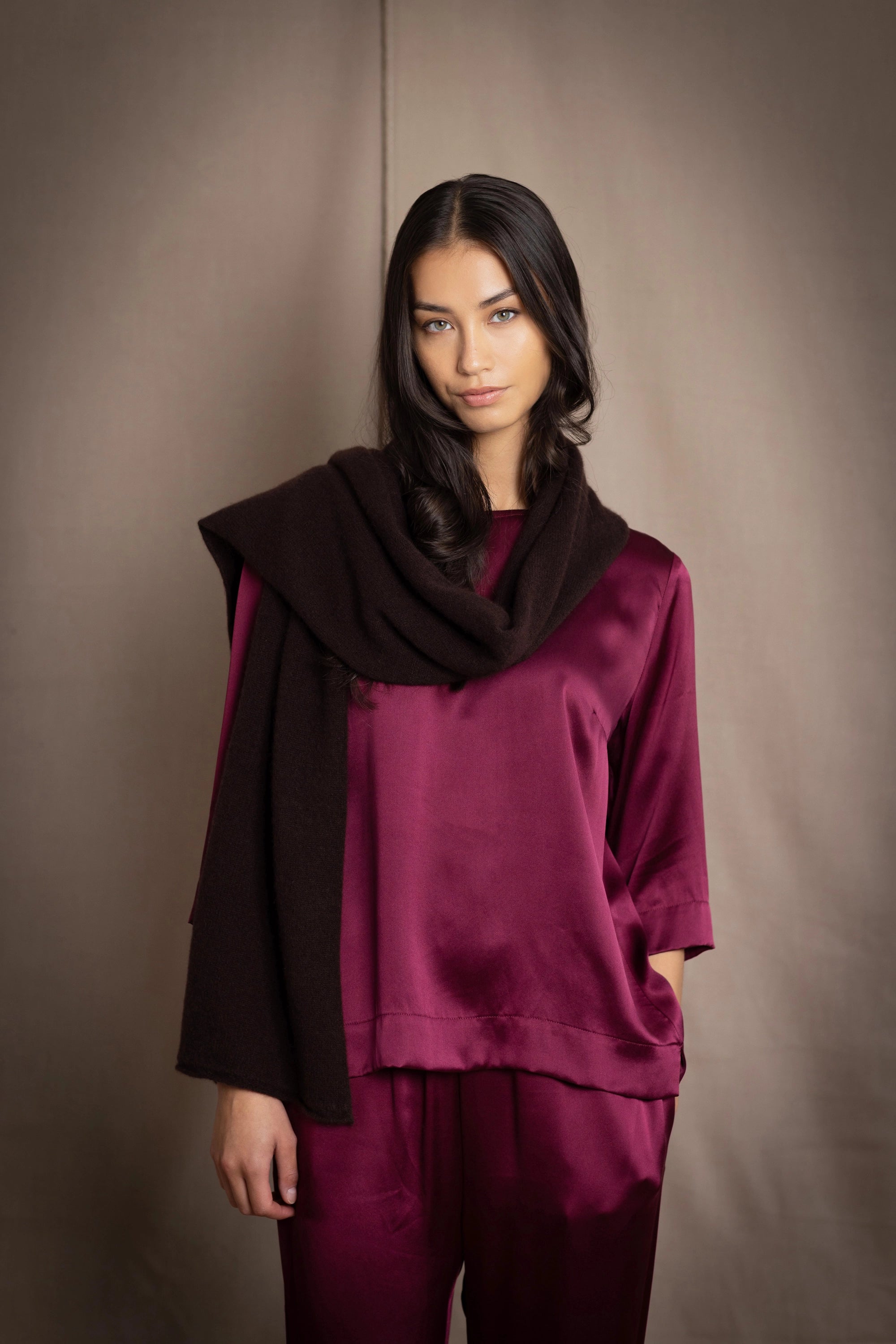 a woman wearing a cashmere scarf in dark brown over burgundy silk clothing
