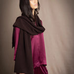 a woman wearing a cashmere scarf in dark brown over burgundy silk clothing