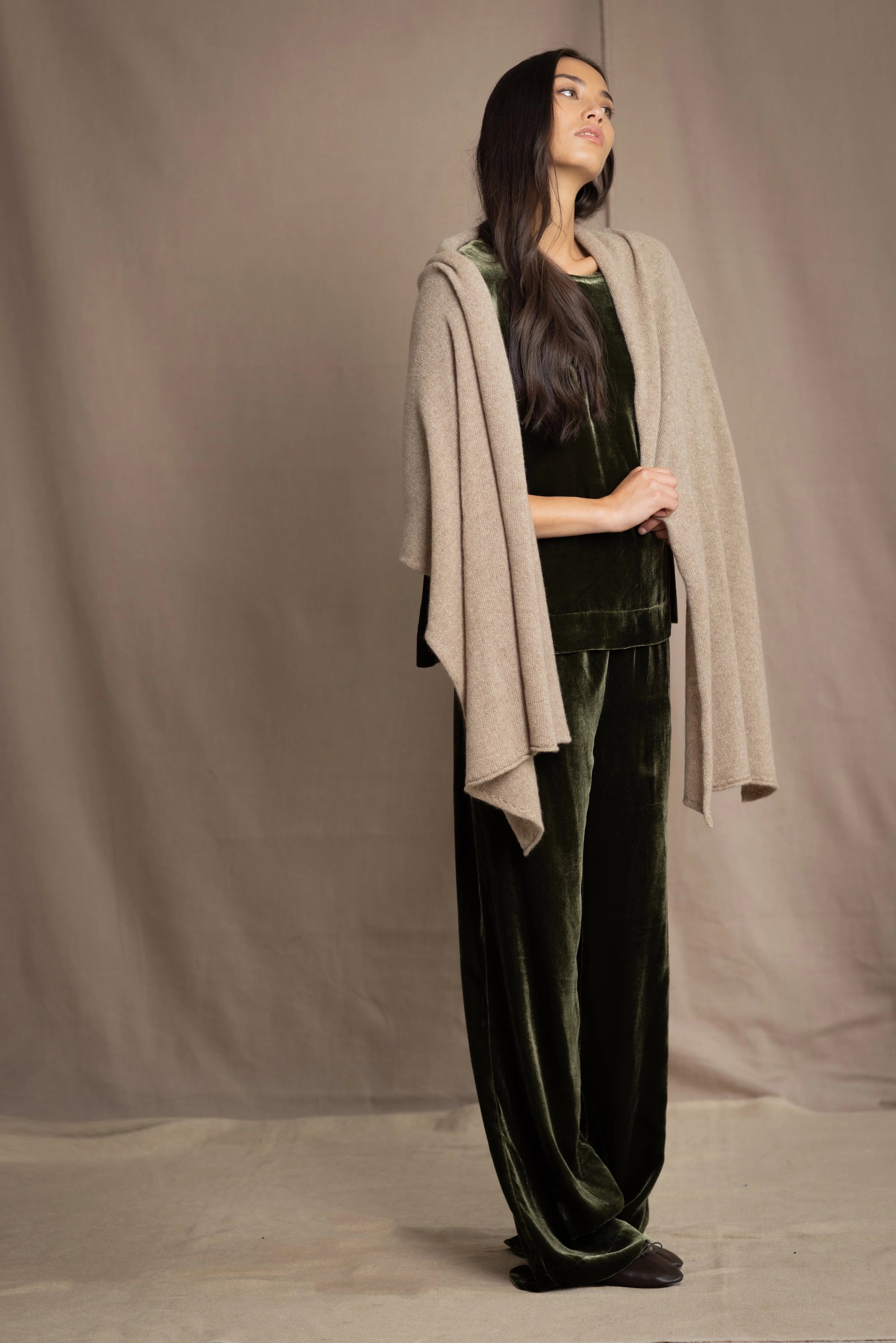 Woman wearing a beige cashmere wrap in beige with gold metallic lurex over green velvet outfit