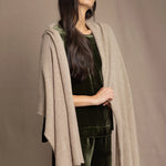 Woman wearing a beige cashmere wrap in beige with gold metallic lurex over green velvet outfit