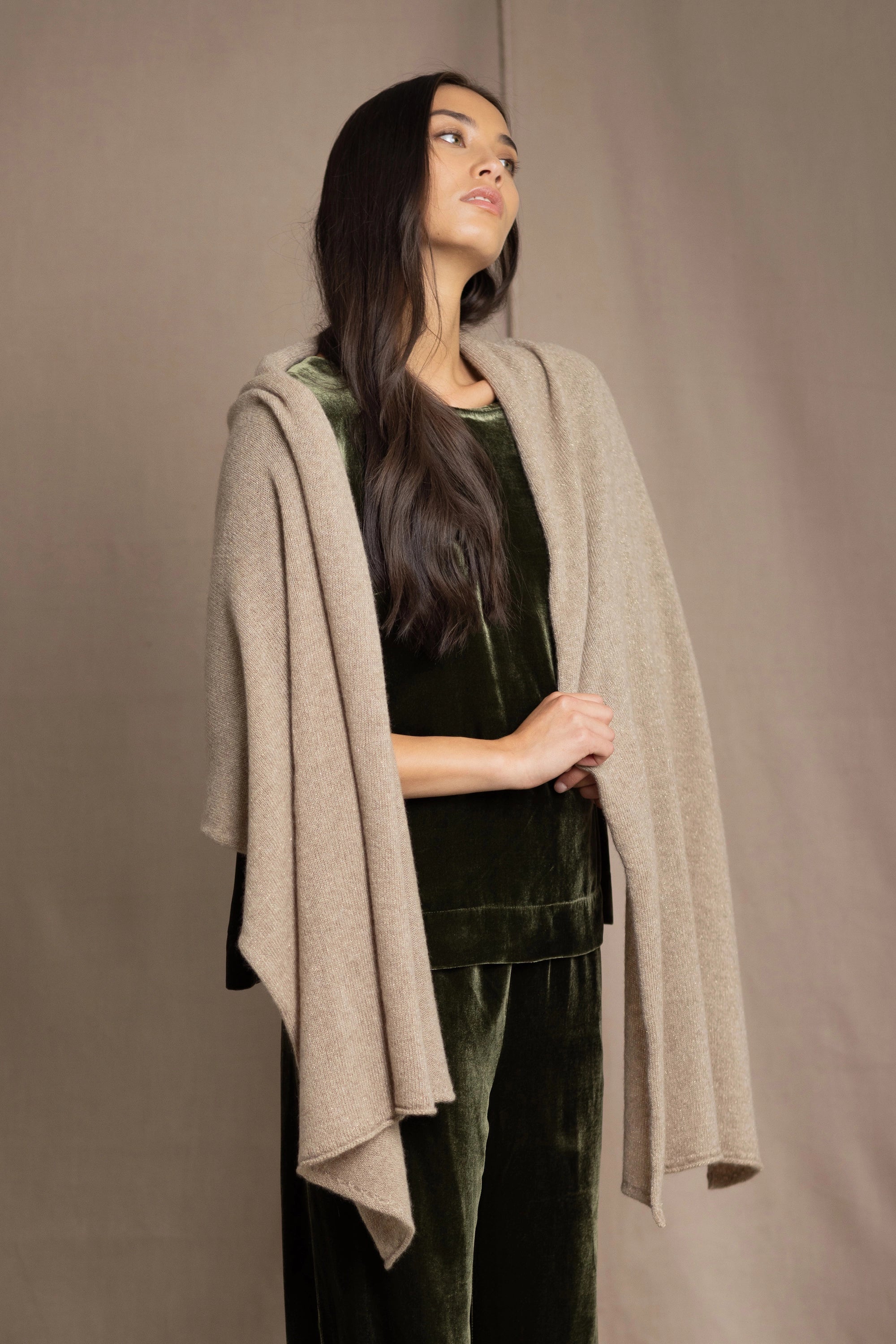 Woman wearing a beige cashmere wrap in beige with gold metallic lurex over green velvet outfit
