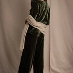 Woman wearing a beige cashmere wrap in beige with gold metallic lurex over green velvet outfit