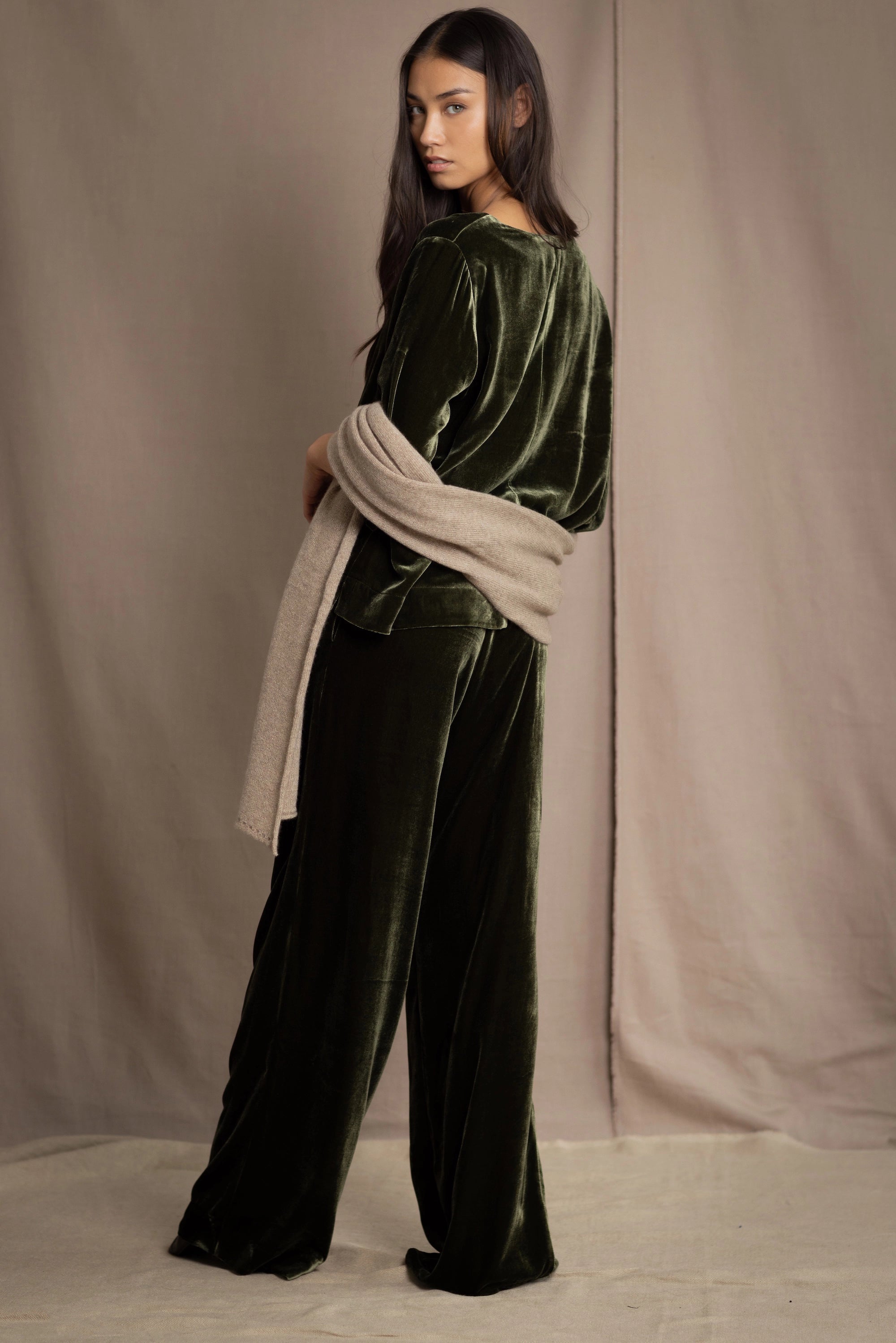 Woman wearing a beige cashmere wrap in beige with gold metallic lurex over green velvet outfit