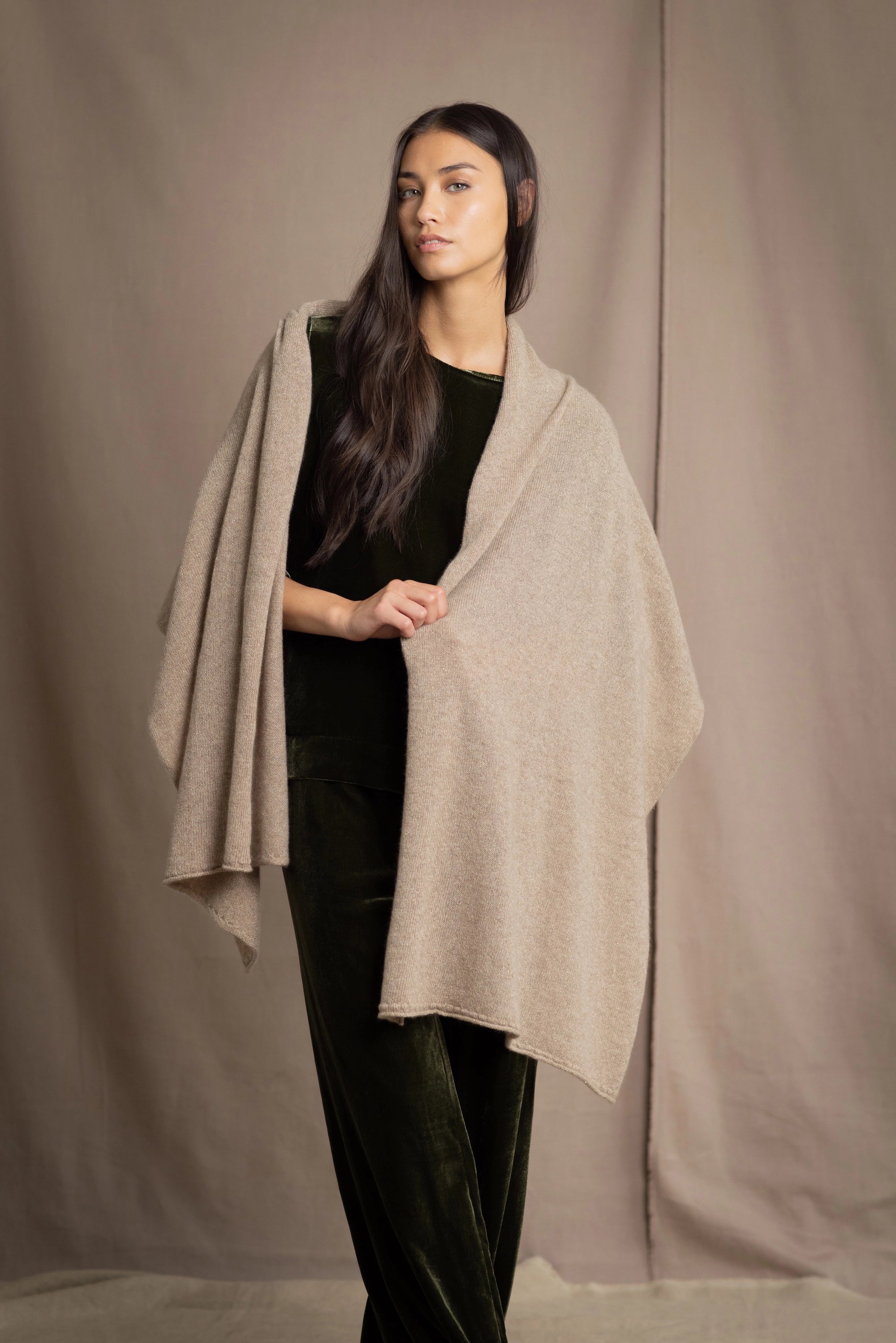 Woman wearing a beige cashmere wrap in beige with gold metallic lurex over green velvet outfit