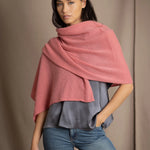 a woman wearing a cashmere wrap scarf in dusty rose pink