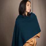 a woman wearing a cashmere wrap scarf in teal over bronze silk clothing
