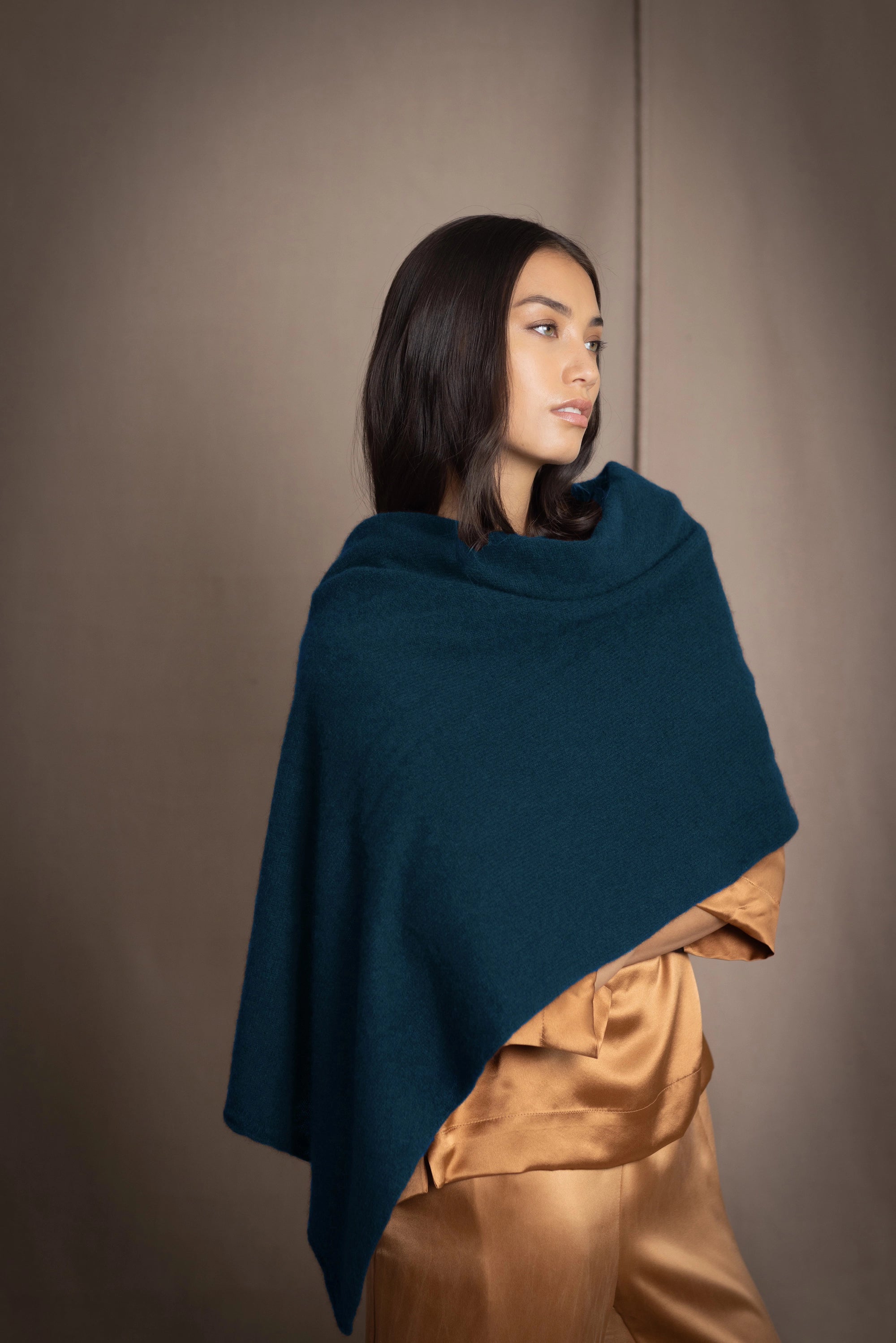 a woman wearing a cashmere wrap scarf in teal over bronze silk clothing